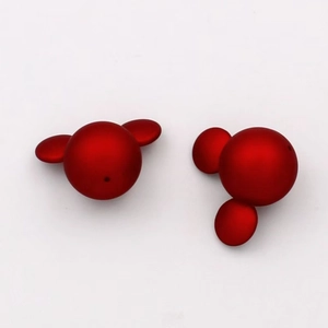 Macro shot of red Mickey-shaped matte stud earrings showing front and back detail