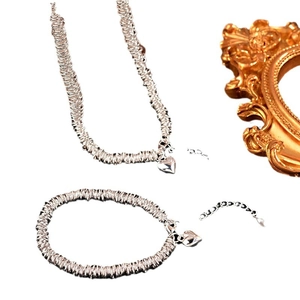 Silver heart pendant jewelry set featuring layered coil chain necklace and bracelet