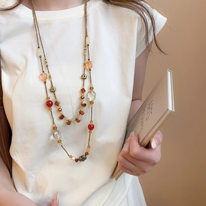 Detail of vintage double-layer necklace with amber beads and crystals on a white tee