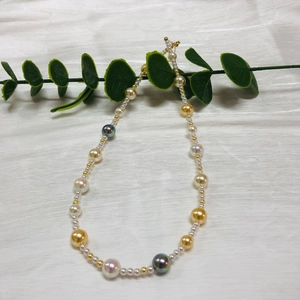 Close-up of multicolor Akoya pearls necklace with gold spacer beads on fabric