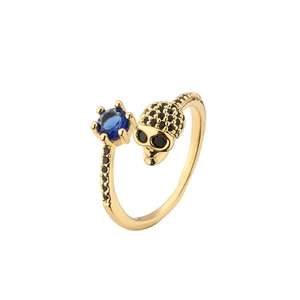 Adjustable gold skull ring with blue zircon and black pave stones on white background