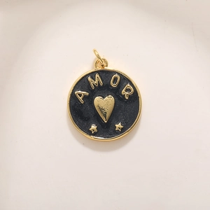 Détail macro du pendentif AMOR plaqué or avec émail noir et motifs cœur et étoiles