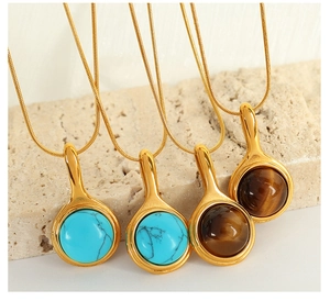 Detail view of 18K gold snake chain necklaces with turquoise and tiger eye stone pendants