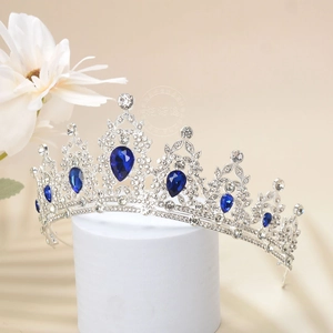 Detail shot of luxurious silver tiara featuring deep blue teardrop rhinestones and crystals