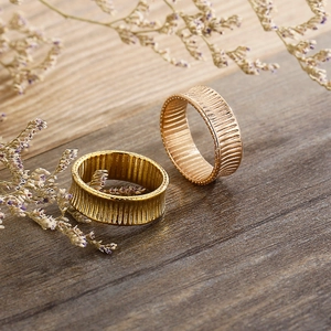 Detailed view of textured 18K gold and rose gold striped rings on a wooden table