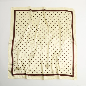 Detail of soft beige polka dot silk scarf with dark brown border and smooth texture