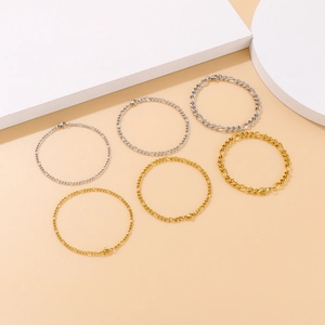 Set of six gold and silver Figaro chain bracelets on minimalist beige background