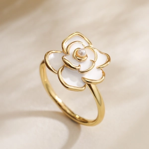 Macro shot of 18K gold plated ring featuring a white enamel camellia and pearl center