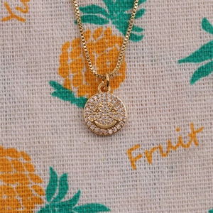 Close-up of gold-plated copper smiling face pendant necklace with sparkling cubic zirconia