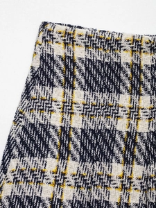 Gros plan sur le tissu en tweed noir et blanc avec des lignes jaunes sur une jupe