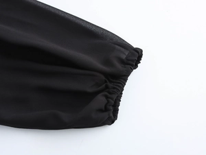Detail view of elastic sleeve cuffs on a black chiffon dress with sheer fabric texture