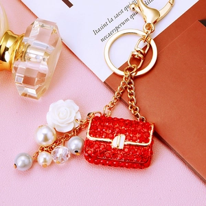 Detail of red rhinestone mini bag keychain with white rose and luxury pearls decoration