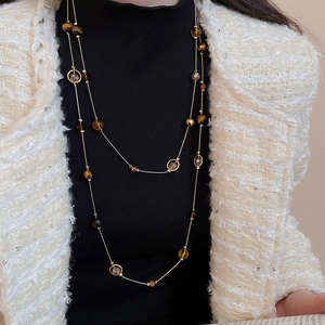 Detail einer doppelreihigen Vintage-Goldkette mit bernsteinfarbenen Perlen auf Schwarz
