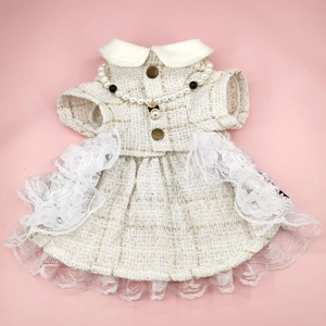 Detailed close-up of white tweed pet dress with pearl necklace and lace ruffled hem