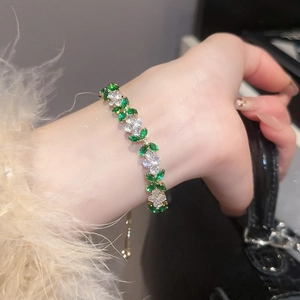 Detail of green zircon flower bracelet with gold adjustable chain on woman's wrist