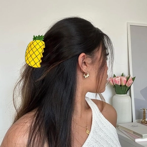 Close-up of a yellow pineapple hair claw clip worn on hair for a creative summer look