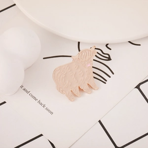 Detail shot of cute enamel highland cow pin with gold edges on white display card