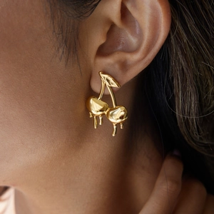Macro shot of gold cherry stud earrings with a melting lava design on female ear