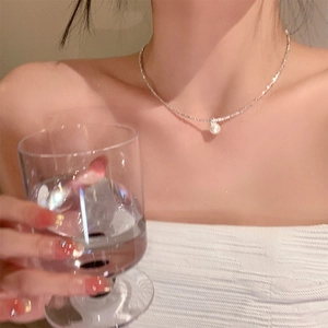Elegante Silberkette mit weißem Perlenanhänger an einem Modell bei weichem Licht
