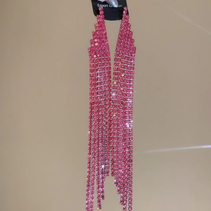 Detailed view of long tassel earrings with pink rhinestones set in a trapezoid metal base