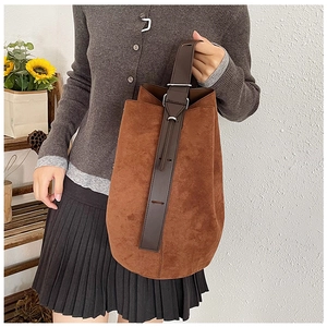 Detail of caramel suede tote bag featuring leather handles and minimalist metal buckle