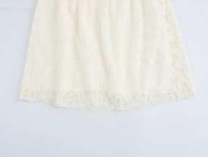 Detail of white lace dress hem featuring intricate floral patterns and sheer fabric texture