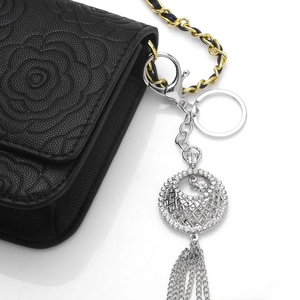Porte-clés argenté avec cristaux et longues franges métalliques sur sac en cuir noir