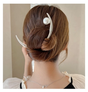 Elegant silver crescent hair pin with a large pearl detail worn in a classic bun hairstyle