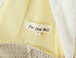 Gros plan de l'étiquette de cou tissée taille S sur la robe jaune sans manches à pois