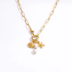 Macro detail of golden paperclip chain necklace with starfish, shell and pearl charms