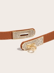 Detail of a brown Saffiano leather belt featuring a gold swivel lock buckle with rhinestones