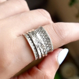 Close-up of vintage silver floral textured wide band ring with handcrafted details
