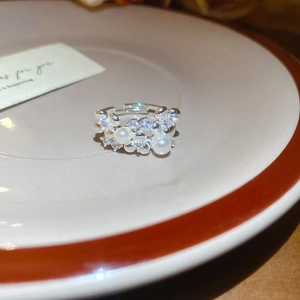 Close-up of lace flower ring with pearls and zircons on a decorative ceramic dish