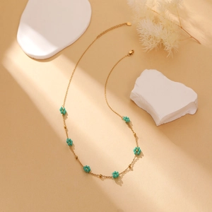 Detail of gold flower necklace with green bead petals and adjustable lobster clasp