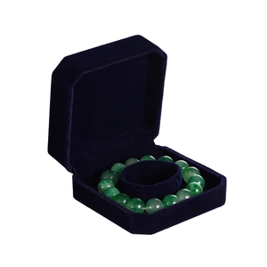 Detail of dark blue velvet jewelry box with green jade bead bracelet inside