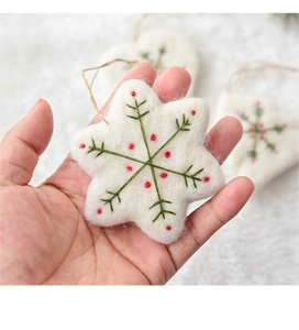 Detail of wool felt snowflake ornament with green stitching and red dots for Christmas DIY