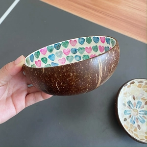 Natural coconut shell bowl with colorful heart pattern held in hand for home decor