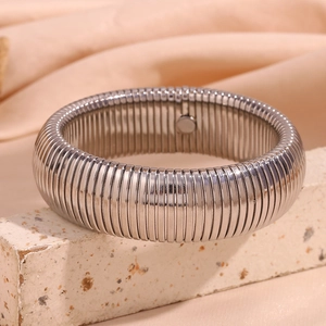 Macro detail of 20mm wide silver textured snake chain bangle on a stone pedestal