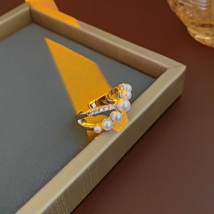 Macro shot of silver ring with pearls and pavé cubic zirconia on grey tray