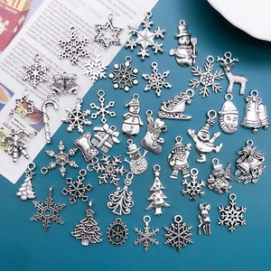 Flat lay macro of vintage silver Christmas charms featuring snowflakes and Santa shapes