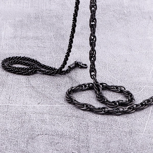 Close-up of black titanium steel interlocking curb chain and textured bead necklace with clasp