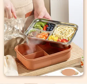 Detail showing hot water being poured into the base of a 3-compartment stainless steel bento box