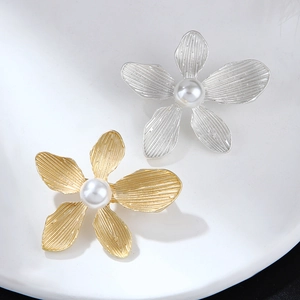 Detailed view of textured metal flower brooches with central pearls in gold and silver