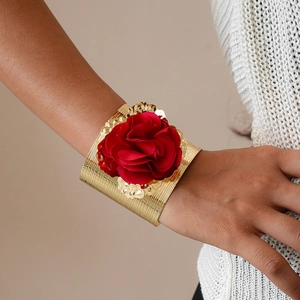 Detail view of bold red fabric flower on a textured gold metal arm cuff bracelet