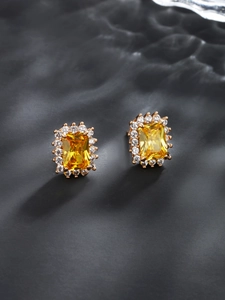 Macro detail of rectangle yellow gemstone earrings with halo diamonds and gold plating