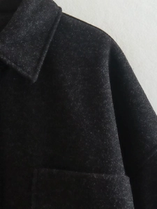 Gros plan du revers de manteau en laine gris foncé montrant la texture épaisse du tissu