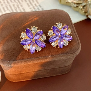 Dettaglio macro di orecchini a fiore in cristallo viola con placcatura in oro e strass