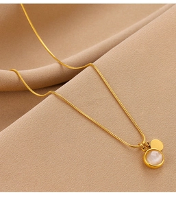 Détail du collier doré avec pendentif double opale sur un fond en tissu texturé