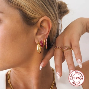 Detailed view of model wearing S925 sterling silver gold earrings and red stone rings