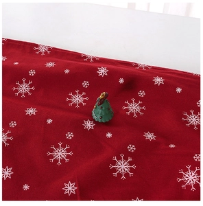 Close-up of red Christmas table runner with white snowflake patterns and knitted texture